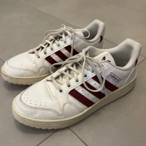 Adidas sneakers vit/röd - Säljer ett par vita Adidas med röda detaljer. Använda en del men fortfarande i bra skick🙏