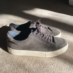 mocka sneakers från Vagabond - Snygga sneakers från Vagabond i mörkgrå mocka med rund tå och platt vit sula. Skorna har klassisk snörning och en stilren design som passar till jeans eller chinos. Insidan är fodrad i mörkblått tyg och yttermaterialet är mjukt och matt.