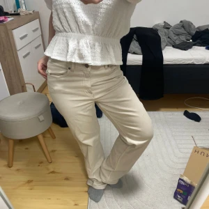 Beige raka jeans med normal passform - Snygga beige jeans med rak siluett och klassisk femficksdesign. Byxorna har normal midja och är tillverkade i mjukt bomullsmaterial som ger en skön känsla. Perfekt för dig som gillar en clean och enkel look.