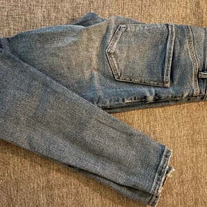 Blå low waist jeans Stradivarius - Säljer ett par blå jeans från Stradivarius i storlek 34. Modellen är low waist med klassiska bakfickor och raka ben. Jeansen har en snygg tvätt och är tillverkade i bomullsmix för en bekväm känsla.