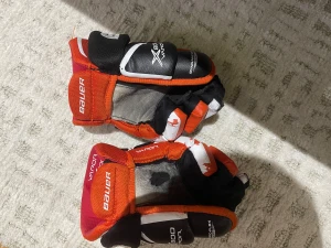 Bauer Vapor X800 hockeyhandskar - Säljer ett par Bauer Vapor X800 hockeyhandskar i svart, rött och vitt. Handskarna har en sportig design med tydliga loggor och extra skydd på ovansidan. Perfekta för dig som spelar hockey och vill ha bra grepp och komfort på isen.
