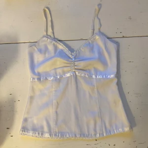  🍒Vintage babydoll linnetopp i satin🍒 - 🍒THEA TOP🍒Så snygg babydoll linnetopp i matt satin med smala reglerbara axelband från MQ. Toppen har fina spetsdetaljer, glansiga pärlfärgade band, en smockad rygg och dragkedja i sidan. Missa inte denna! 🐚
