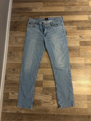 Ljusblå Lee jeans i ekologisk bomull - Säljer ett par ljusblå jeans från Lee, tillverkade i ekologisk bomull. Klassisk femficksmodell med Lee-lapp bak i brunt och raka ben. Jeansen har normal passform och är perfekta för dig som gillar en enkel och clean look.