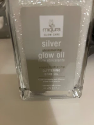 Miqura Silver Shimmering Glow Oil - Silverfärgad, glittrande glow oil från Miqura Glow Care. Oljan är super återfuktande och passar normal till torr hud. Kommer i en snygg, fyrkantig glasflaska med pipett och har en skimrande finish som ger huden extra lyster.