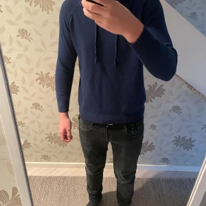 Marinblå Kashmir hoddie med huva och snörning - Snygg marinblå hoodie med huva och snörning framtill. Tröjan har långärmade ärmar och ribbade muddar vid ärmslut och nederkant. Perfekt för dig som gillar en enkel och stilren look. Materialet känns mjukt och skönt mot huden.