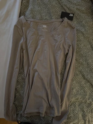 Beige långärmad topp från 157 - En enkel och stilren beige långärmad topp från 157, gjord i mjuk bomull med lite stretch för skön passform. Rundad halsringning och smal siluett, perfekt att matcha med jeans eller kjol. Materialet är 95% bomull och 5% elastan.