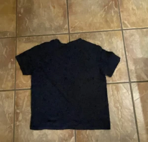 Mörkblå t-shirt från Lacoste - Snygg mörkblå t-shirt från Lacoste med klassisk krokodillogga broderad på bröstet. T-shirten har rund hals och korta ärmar, tillverkad i mjuk bomull som känns skön mot huden. Perfekt för dig som gillar stilrena och ikoniska plagg.