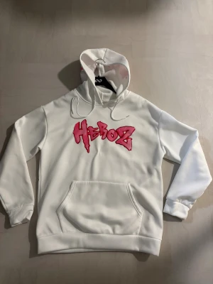 Hoodie  - Vit hoodie med rosa tryck på fram och baksida. Aldrig använd. Storlek L. Kan även funka som M.
