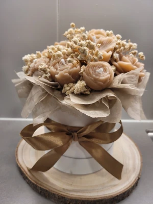 Ljusbukett - Unikt arrangemang med handgjutna ljus i form av beige blommor, dekorerat med torkade vita blommor och inslaget i transparent papper. Snyggt placerat i en vit rund ask med satinband i brons. Perfekt som inredningsdetalj eller present.
