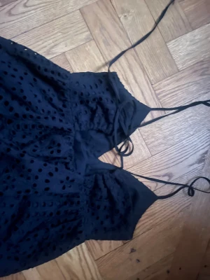 Svart långklänning med broderade hål - Svart långklänning med tunna axelband och v-ringad hals. 🍒💕Klänningen har ett snyggt broderat hålmönster över hela tyget som ger en cool och unik look.❣️☎️Passformen är normal och materialet känns som bomull. Perfekt för dig som gillar detaljer och stilrena färger.❤️❤️