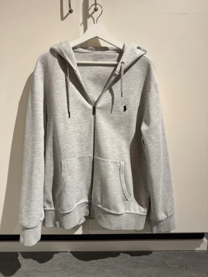Grå zip hoodie Ralph Lauren - Snygg grå zip hoodie från Ralph Lauren Perfekt för chill dagar och har en loose passform. Tveka inte att höra av dig vid frågor!
