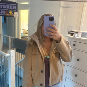 Beige jacka med huva och knappar - Snygg beige jacka i med stor huva och coola knappar framtill. Jackan har två fickor, markerad krage.