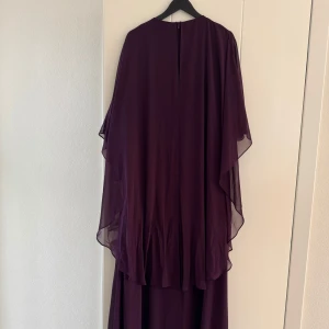 Lång vinröd klänning med cape - Storlek 40-42. 