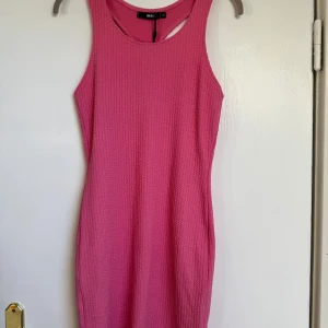 Rosa ribbad kortklänning från BIK BOK - Säljer en snygg rosa kortklänning från BIK BOK i ribbad. Klänningen är ärmlös med racerback och har en tight passform som framhäver figuren. Perfekt för dig som gillar färg och vill sticka ut lite extra.