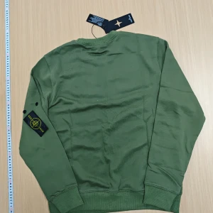 Grön sweatshirt från Stone Island M - Snygg grön sweatshirt från Stone Island endas använd 1 gång, med klassisk rund hals och ribbade muddar. Tröjan har den ikoniska loggan på vänster ärm och är tillverkad i mjuk bomull. Perfekt för dig som vill ha en stilren och trendig look.🌳☘️