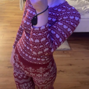  jultröja med hjärtan och julbyxor med snöflingor - Supermysig julsett. Byxorna och tröjan matchar inte som ni ser på bilderna men säljer dom ihop då jag använt de som ett sett och uppskattat de enormt! Storlek är i barn på tröjan och byxorna i S. Mer frågor skriv🩷