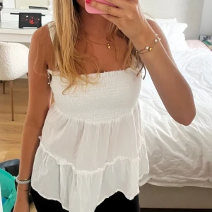 Vit volangig linnetopp med smock - Supersöt vit linnetopp med smockad överdel och breda axelband. Toppen har volanger i två lager och en luftig, flowy passform. Baksidan har snygga banddetaljer som ger en extra touch. Perfekt för varma dagar och enkel att styla till jeans eller kjol🤍🤍🤍