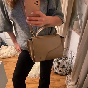 Beige axelväska i skinn - Säljer en stilren beige axelväska i skinn med både handtag och axelrem. Väskan har en snygg, mjukt rundad lockdesign och är perfekt för dig som vill ha en klassisk men trendig look. Rymmer det viktigaste och passar till många outfits. ATP atelier arezzo, använd men i fint skick. Priset är diskuterbarr