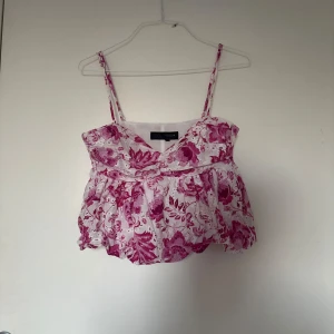 Blommig rosa och vit linnetopp Zara - Supersöt linnetopp från Zara med rosa och vita blommor. Toppen har smala axelband, v-ringning och en luftig, voluminös passform. Perfekt för varma dagar och ger en romantisk vibe till din outfit.