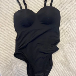 Svart body med vadderingoch hakknäppning - Svart body med tre knäppen och vadering i bh På mig passar den som har 75b men det är ju olika fråm person till person