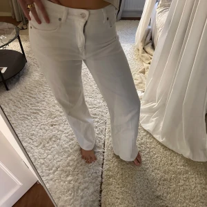 Vita raka jeans med hög midja - Säljer ett par vita jeans med raka ben och hög midja. Byxorna har klassisk femficksdesign, bälteshällor och stängs med knapp och dragkedja. Perfekta för en clean och fräsch look. Materialet är bomull och passformen är normal. Jag brukar ha storlek 36 i jeans men dessa är väldigt små i storlek🥰