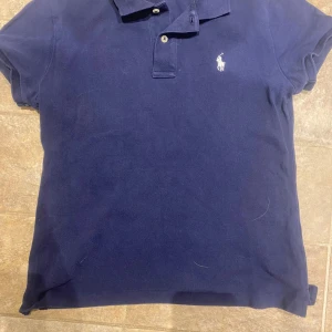 Ralph lauren pike - En fett slim Ralph lauren piké för extremt billigt pris. Den e navy blue skulle jag säga men med nyanser av ljusare blått i ljus. Den är storlek S fast sitter litet så skulle säga xs-s med tanke den ska sitta tajt.