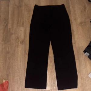 Svarta kostymbyxor från Vero Moda - Klassiska svarta kostymbyxor från Vero Moda med rak passform och diskreta fickor. Byxorna har en stilren look och är perfekta för en clean och snygg outfit. Materialet känns mjukt och följsamt, vilket gör dem bekväma att bära hela dagen.finns ingen lapp med storlek, men är en storlek L, jag är 160cm