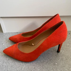 Orangeröda mockapumps från Zara - Snygga orangeröda pumps från Zara i mjuk mocka med spetsig tå och smal klack. Perfekta för dig som vill sticka ut med färg och stil. Klassisk modell som ger en elegant touch till din outfit.