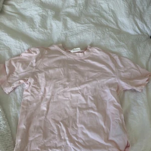Ljusrosa basic t-shirt - Enkel och stilren ljusrosa t-shirt i mjuk bomull. Klassisk passform med rund halsringning och korta ärmar. Perfekt att matcha med jeans eller shorts för en avslappnad look. Tröjan ser skrynklig ut därav att jag tvättat den men stryker man den är den jättefin!