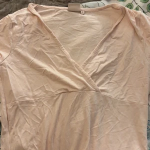 Ljusbeige omlottklänning i bomull - Säljer en ljusbeige omlottklänning i mjuk bomull. Klänningen har v-ringning och korta ärmar, perfekt för varmare dagar. Enkel och stilren design som är lätt att matcha med accessoarer.