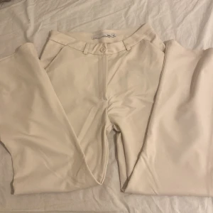 Beiga kostymbyxor från Lager157 - Snygga beiga kostymbyxor från lager157, bootcut. Byxorna är midwaist och är tillverkade i ett slätt, vävt material som känns lyxigt. Perfekta för en clean och stilren look. Storlek XS men passar S