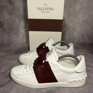 Valentino Rockstud sneakers vit/vinröd - Extremt Snygga Valentino Rockstud Untitled sneakers i vitt och vinröd färg. Skorna är i storlek 43 och är använda en handfull av gånger så 9/10 skick. Box, dustbags, Valentino kort, extra snören fås med. Nypris 8’000kr