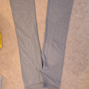 Ljusgrå mjukisbyxor med snörning - Säljer ett par ljusgrå mjukisbyxor med dragsko i midjan. Byxorna är raka i modellen och tillverkade i mjukt bomullsmaterial, perfekta för chill dagar eller när du vill vara extra bekväm.