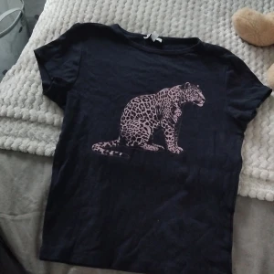 Svart t-shirt med leopardtryck - HAR FLER I DENNA STIL UPPLADDADE‼️‼️‼️Svart t-shirt med coolt leopardtryck på framsidan. Klassisk rund hals och korta ärmar, perfekt för en avslappnad och trendig stil. Mjuk och skön bomullskänsla, passar till jeans eller shorts.