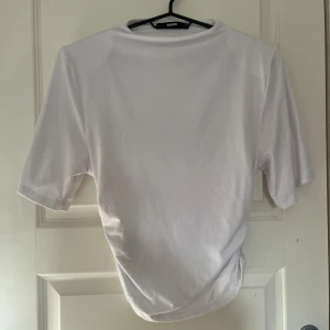 Vit t-shirt med rynkade detaljer Bik Bok - Vit t-shirt från Bik Bok med korta ärmar och snygga rynkade detaljer på sidan. Enkel och stilren design i mjuk bomull, perfekt till jeans eller kjol. Klassisk rund halsringning och relaxed fit. Sparsamt använd, max 2 gånger💕🥰