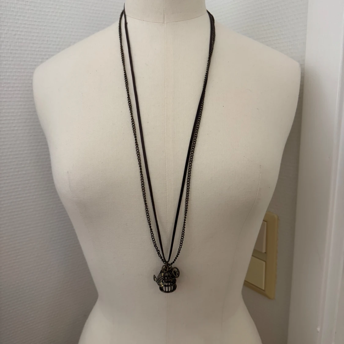 Långt halsband med bur och fågel