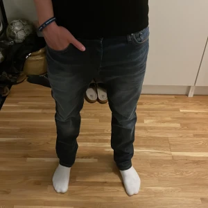 Jack & Jones Jeans - Säljer ett par mörkblå Jack and Jones jeans med snygg tvätt och klassisk femficksdesign. Jeansen har raka ben och normal passform, med diskreta slitningar framtill för en cool look. Materialet är mjukt och stretchigt jeans för extra komfort. NOTERA! Jeansen är i modellen / slim fit straight/Tim storlek 29/30 men passar mig riktigt bra för o vara 181 o väga 70kg nypris: 990kr använda en sommar inga defekter!