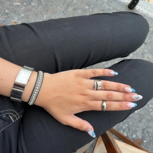 DKNY klocka  - En stilren silvrig klocka från DKNY i väldigt fint skick! den går att göra mindre i diametern ifall det önskas☺️Som ni ser är den väldigt fin att mixa olika smycken och assessorer med. Fråga gärna om fler bilder eller övriga frågor! Klockan fungerar och har batteri i sig