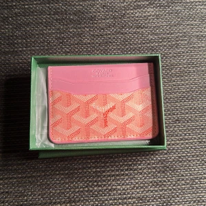 Rosa  plånbok med mönster - Supersnygg plånbok från  i rosa och orange med deras ikoniska mönster. Plånboken har flera kortfack och är tillverkad i skinn. Perfekt för dig som vill ha något unikt och trendigt i väskan.