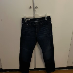 Mörkblå jeans - Snygga mörkblå Jack and Jones  jeans med klassisk femficksdesign och diskreta slitningar framtill. Jeansen har en slim passform och är tillverkade i stretchigt denim för extra komfort. Perfekt för dig som gillar stilrena och moderna jeans.
