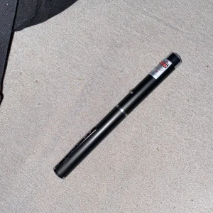 Laserpekare Svart - Kraftfull svart laserpekare med metallkropp och fickklämma. Utrustad med varningsetikett och tryckknapp. Fungerar utmärkt och ger stark laserstråle, perfekt för presentationer eller utomhusbruk. Inga synliga defekter eller slitage. Batteri ingår 