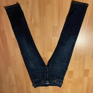 Mörkblå jeans från GANT - Snygga mörkblå jeans från GANT med klassisk femficksdesign och kontrastsömmar. Jeansen har rak passform och är tillverkade i slitstarkt denimtyg. Perfekta för dig som gillar en stilren och tidlös look.