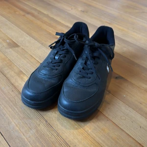 Polo Ralph Lauren skor - Endast använda 1 gång. Snygga svarta skor från Polo Ralph Lauren med klassisk låg profil och rund tå. Bra för mer formella sammanhang. Skorna är gjorda av läder. Namn: Heritage Court II Leather. Nypris: 1645kr