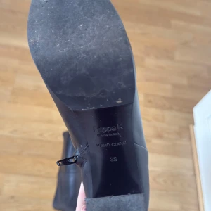 Svarta skinnstövlar från Filippa K - Snygga svarta stövlar från Filippa K i äkta skinn med rund tå och låg klack. Stövlarna har en rejäl dragkedja längs hela skaftet som ger en cool detalj. Perfekt till höst och vinter för en stilren look.