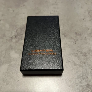 Elektrisk USB-tändare - Elegant elektrisk USB-tändare i svart med blå LED-indikator. Levereras i originalförpackning. Uppladdningsbar och vindskyddad, perfekt för både inomhus- och utomhusbruk. Produkten ser oanvänd ut och är i nyskick utan synligt slitage.