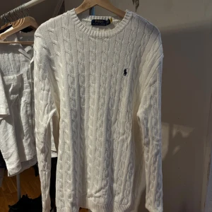 Vit kabelstickad Polo Ralph Lauren - Vit kabelstickad tröja från Polo Ralph Lauren Perfekt för dig som gillar stilrena och tidlösa plagg. Säljer då jag fick den i present men den var inte min stil så har jag aldrig använt den, HELT OANVÄND!!!!!