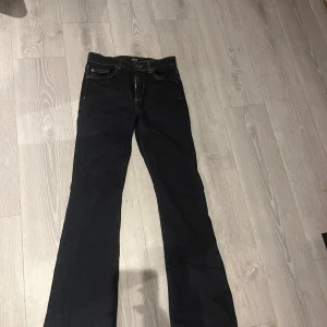 Svarta bootcut jeans från ONLY - Snygga svarta jeans från ONLY med bootcut-modell och klassiska kontrastsömmar. Jeansen har fem fickor och dragkedja med knapp framtill. Perfekta för dig som gillar en tidlös look med lite utsvängda ben. Materialet är jeans med en skön känsla.
