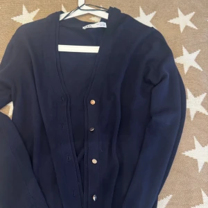Mörkblå kofta från Zara, storlek S - Snygg mörkblå kofta från Zara i storlek S. Koftan har långa ärmar, djup v-ringning och knappar framtill. Tillverkad i mjukt stickat material som känns skönt mot huden. Perfekt att slänga över en t-shirt eller linne för en chill look.Aldig använd!