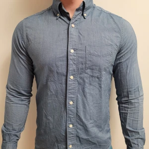 Blå Oxfordskjorta från GANT - Snygg blå Oxfordskjorta från GANT i storlek S med klassisk button-down krage och bröstficka. Skjortan har vita knappar och är tillverkad i 100% bomull. Passformen är slim och ärmarna är långärmade. Nypris runt 1000kr.