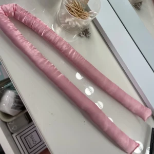 Rosa satin heatlesscurl  - Säljer ett rosa heatlesscurl i satinmaterial, perfekt för att skapa lockar utan värme. Mjuk och böjbar form som enkelt kan formas runt huvudet. Passar dig som vill ha en skonsam stylingrutin. Den har gått sönder lite men det går lätt att sy ihop😊